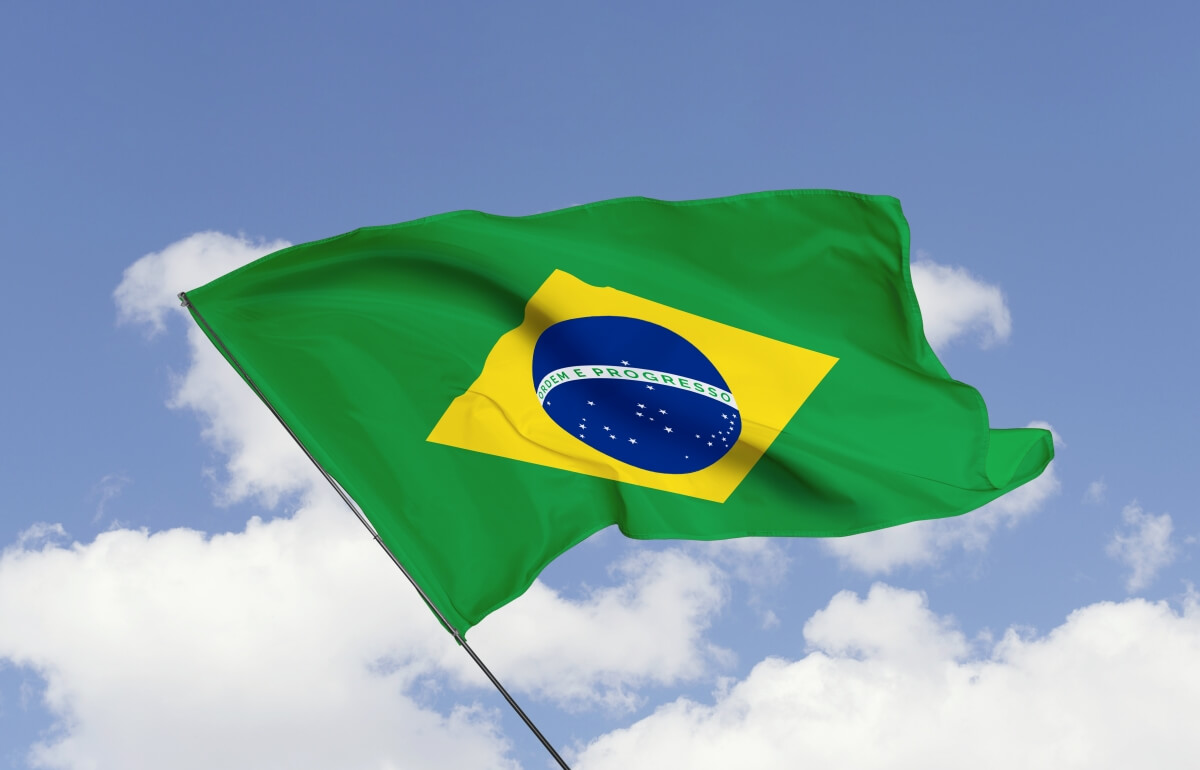 Flaga Brazylii powiewająca na tle błękitnego nieba z chmurami