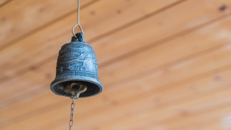 Mały dzwonek metalowy na białym tle - przedmiot na literę D w grze Państwa-Miasta