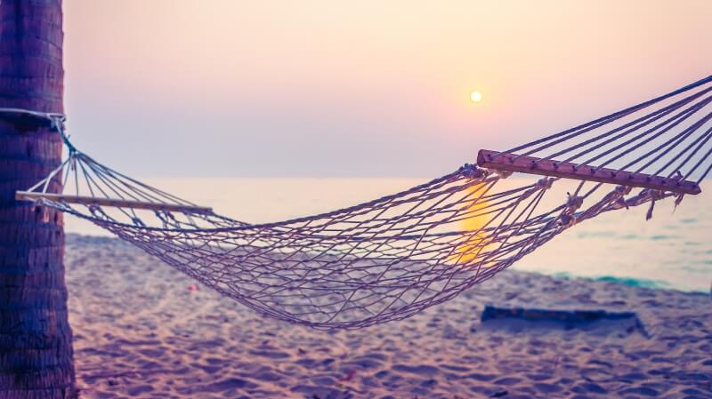 Hamak rozwieszony między palmami na plaży - przedmiot na literę H w grze Państwa-Miasta