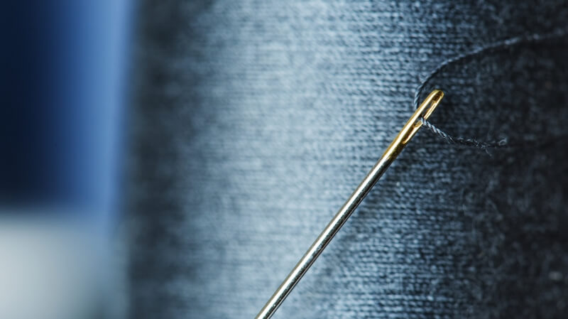 Igła do szycia z nicią na białym tle - przedmiot na literę I w grze Państwa-Miasta