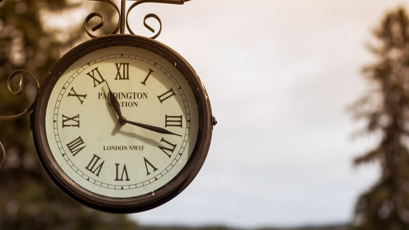 Klasyczny zegar ścienny z białą tarczą i czarnymi wskazówkami - przedmiot na literę Z w grze Państwa-Miasta